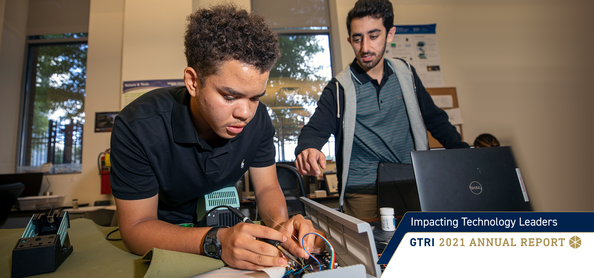 A high school student completing a STEM project with instructor looking over his shoulder. 