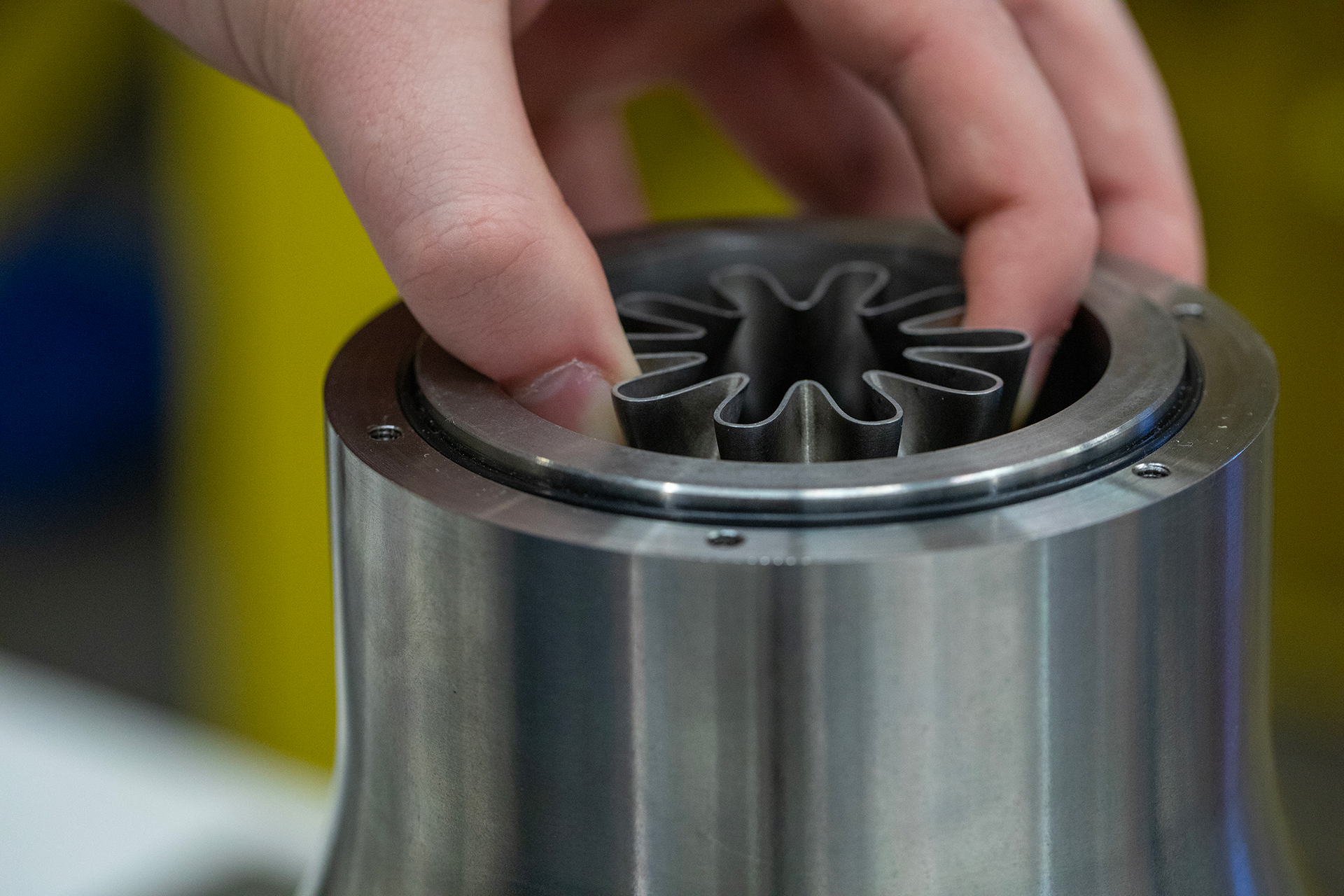 Hand of researcher pushing metal part into metal cylinder.